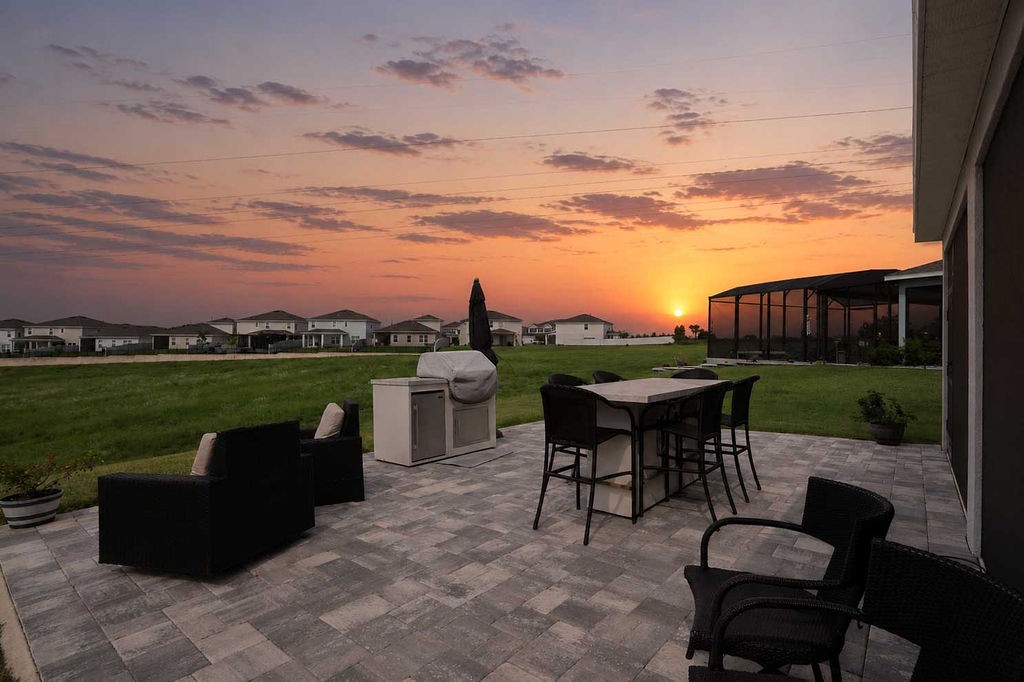 Screened lanai and paver deck at sunset with open green space